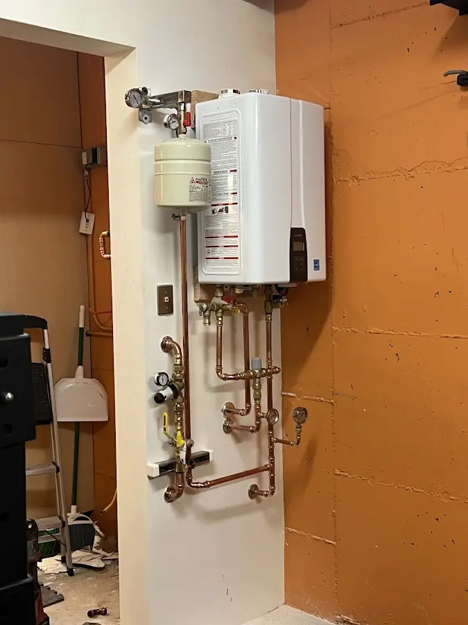 Plumbing technician inspecting water heater connections in Tioga